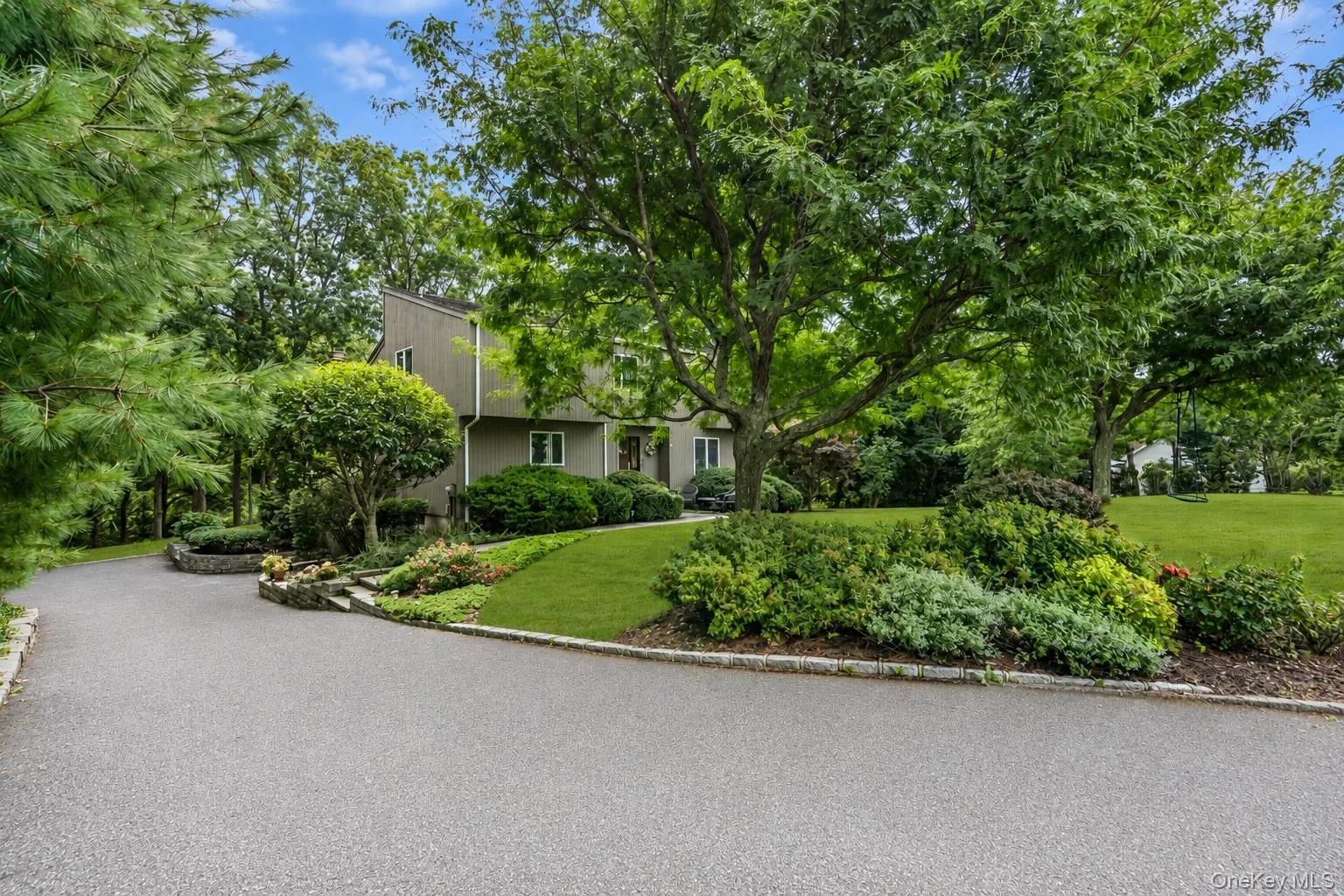 Paved driveway leading to the two car garage, complemented by mature trees and varied landscaping Paved driveway leading to the two car garage, complemented by mature trees and varied landscaping