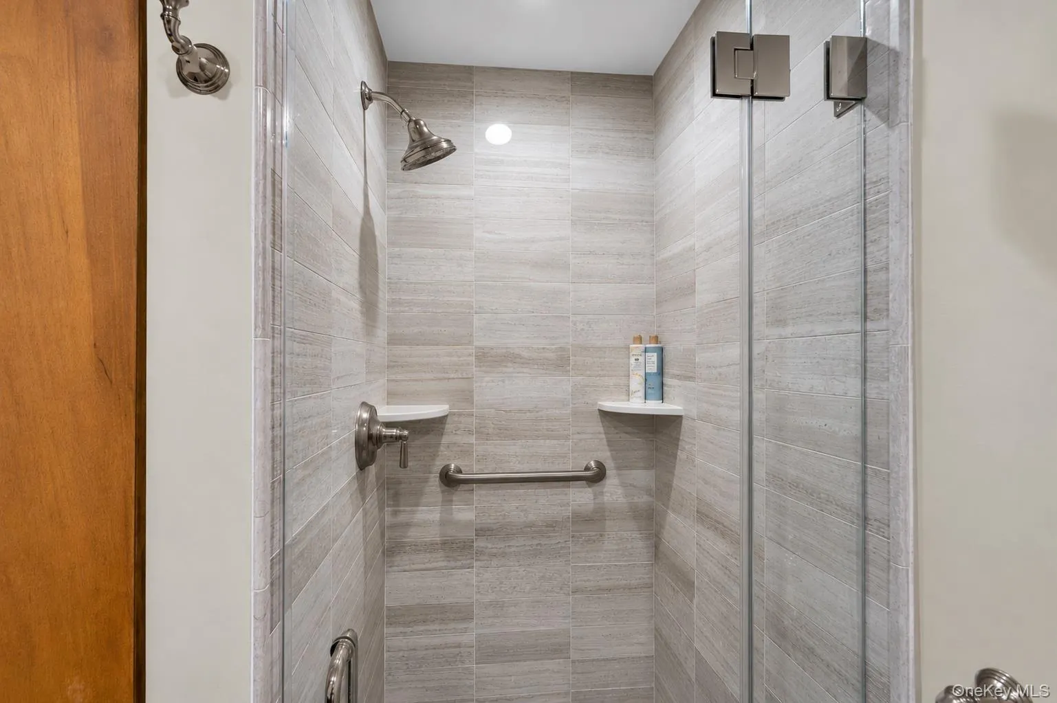 Shower enclosure with full-height tile surround, brushed nickel fixtures, and glass panel door Shower enclosure with full-height tile surround, brushed nickel fixtures, and glass panel door