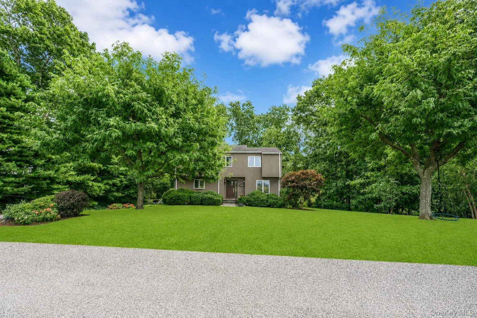 Private road to a Transitional two-story residence with a brown exterior, surrounded by mature trees and lush green landscaping along a vineyard Private road to a Transitional two-story residence with a brown exterior, surrounded by mature trees and lush green landscaping along a vineyard