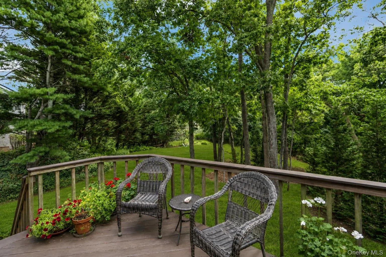 Wood-finish deck with a perimeter railing overlooking a lush, treed landscape with creek view Wood-finish deck with a perimeter railing overlooking a lush, treed landscape with creek view