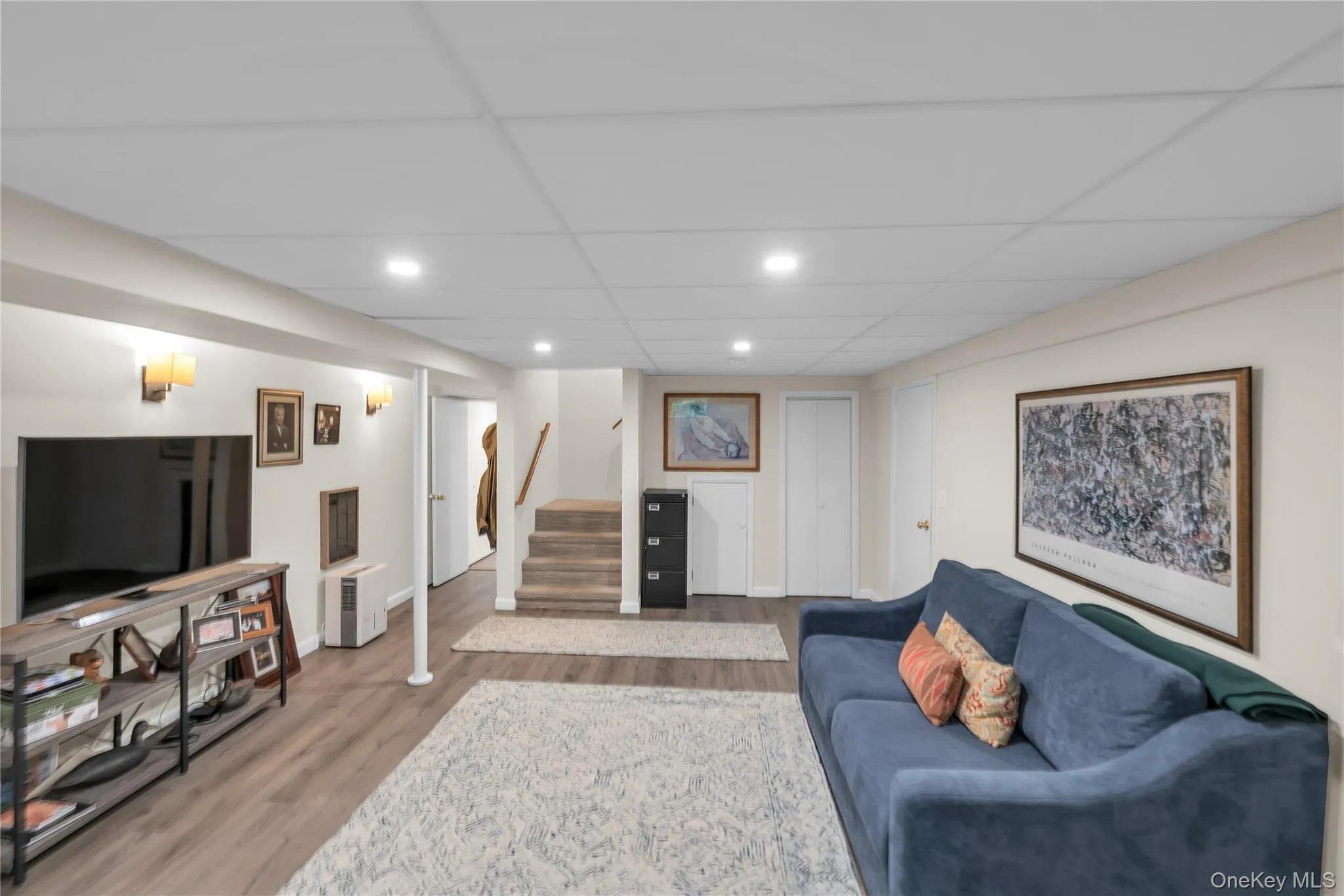 Finished Basement with Media Room and Office Writing Area. Recessed lighting, drop ceiling, wood-finish flooring, wall sconces, and white paneled doors Finished Basement with Media Room and Office Writing Area. Recessed lighting, drop ceiling, wood-finish flooring, wall sconces, and white paneled doors