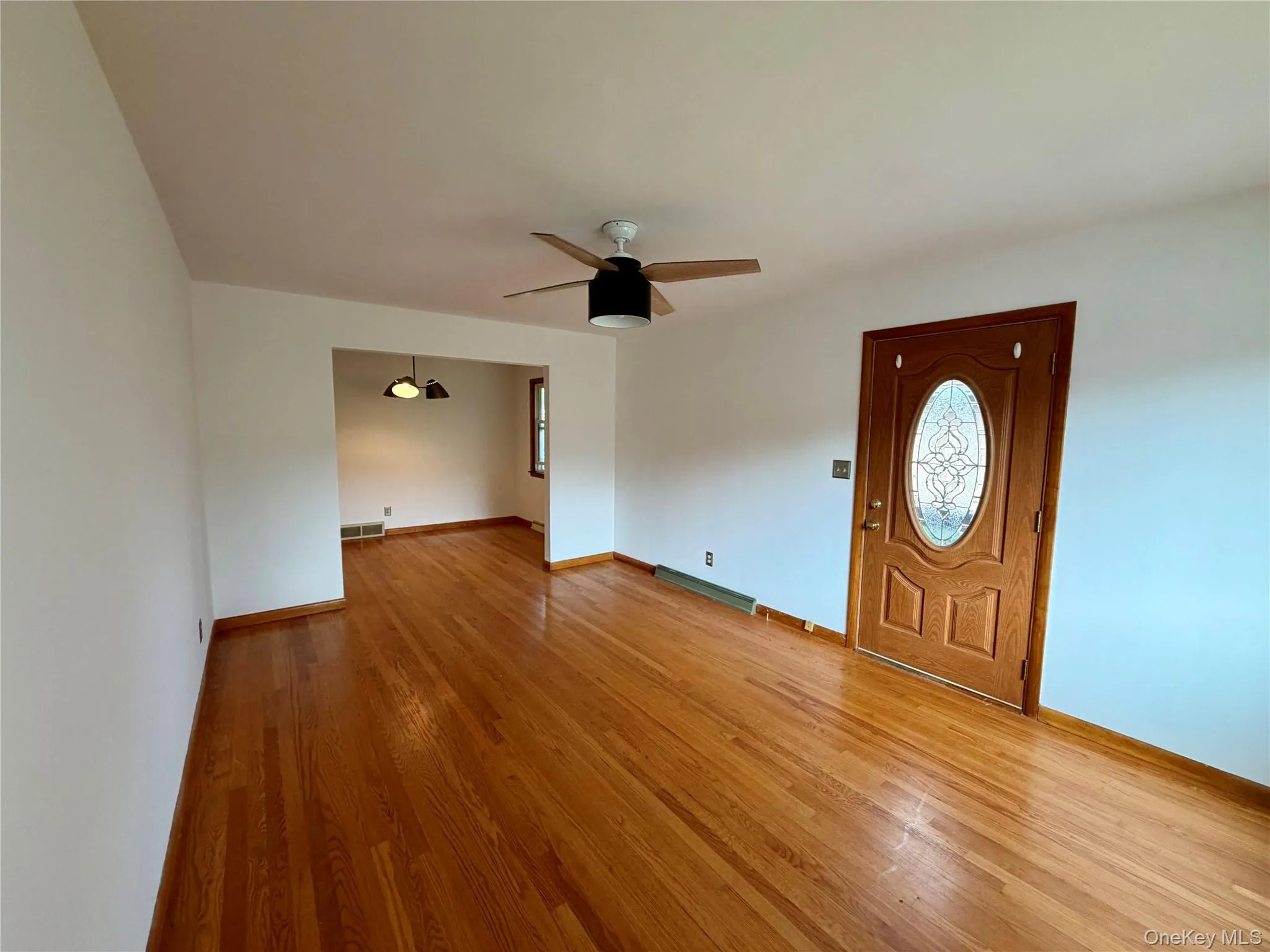 Hardwood flooring throughout, a ceiling fan with light fixture, and an entry door featuring decorative glass Hardwood flooring throughout, a ceiling fan with light fixture, and an entry door featuring decorative glass