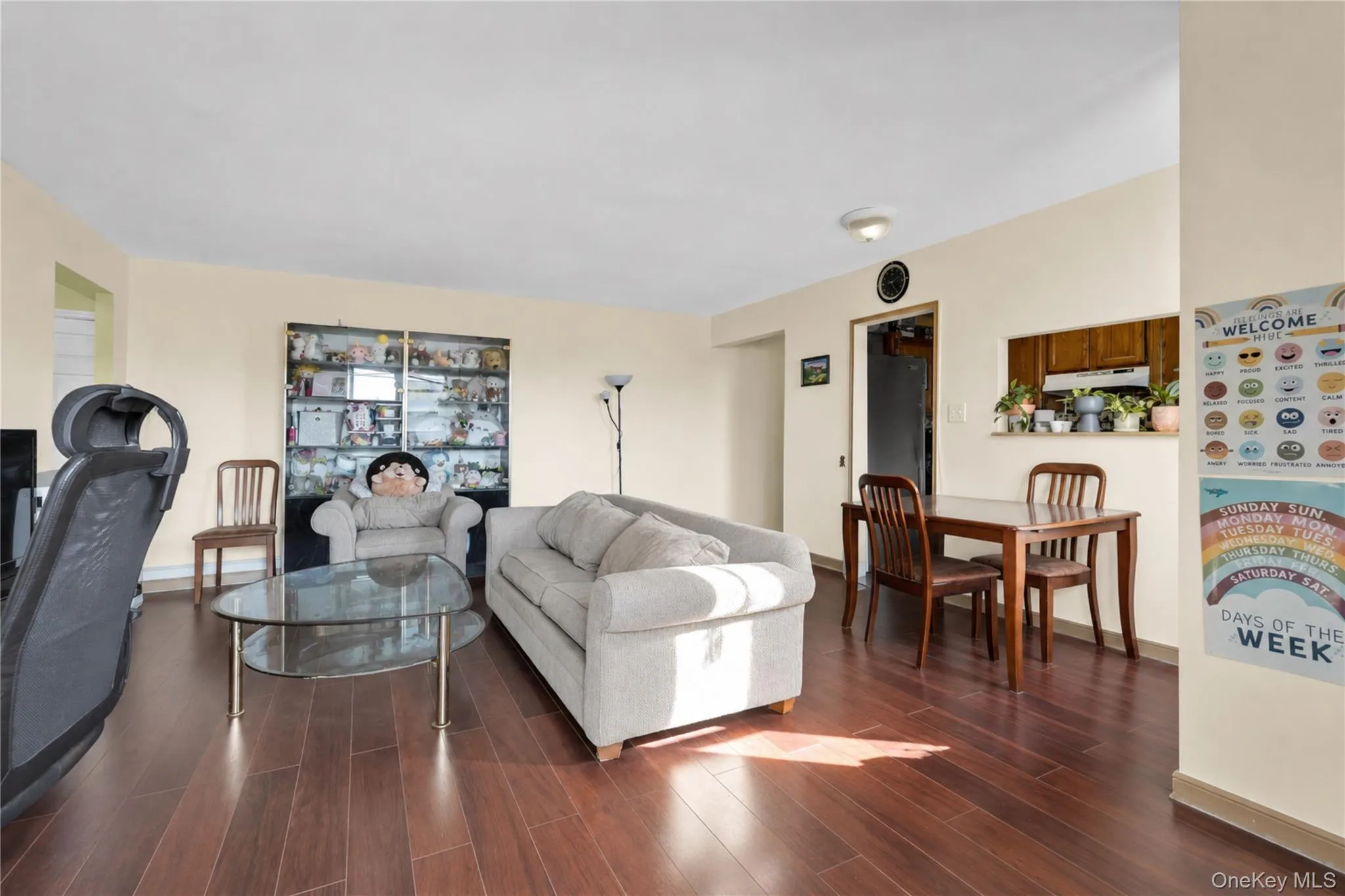 Wood-finish flooring throughout, light-toned wall paint, and a pass-through window to the kitchen Wood-finish flooring throughout, light-toned wall paint, and a pass-through window to the kitchen