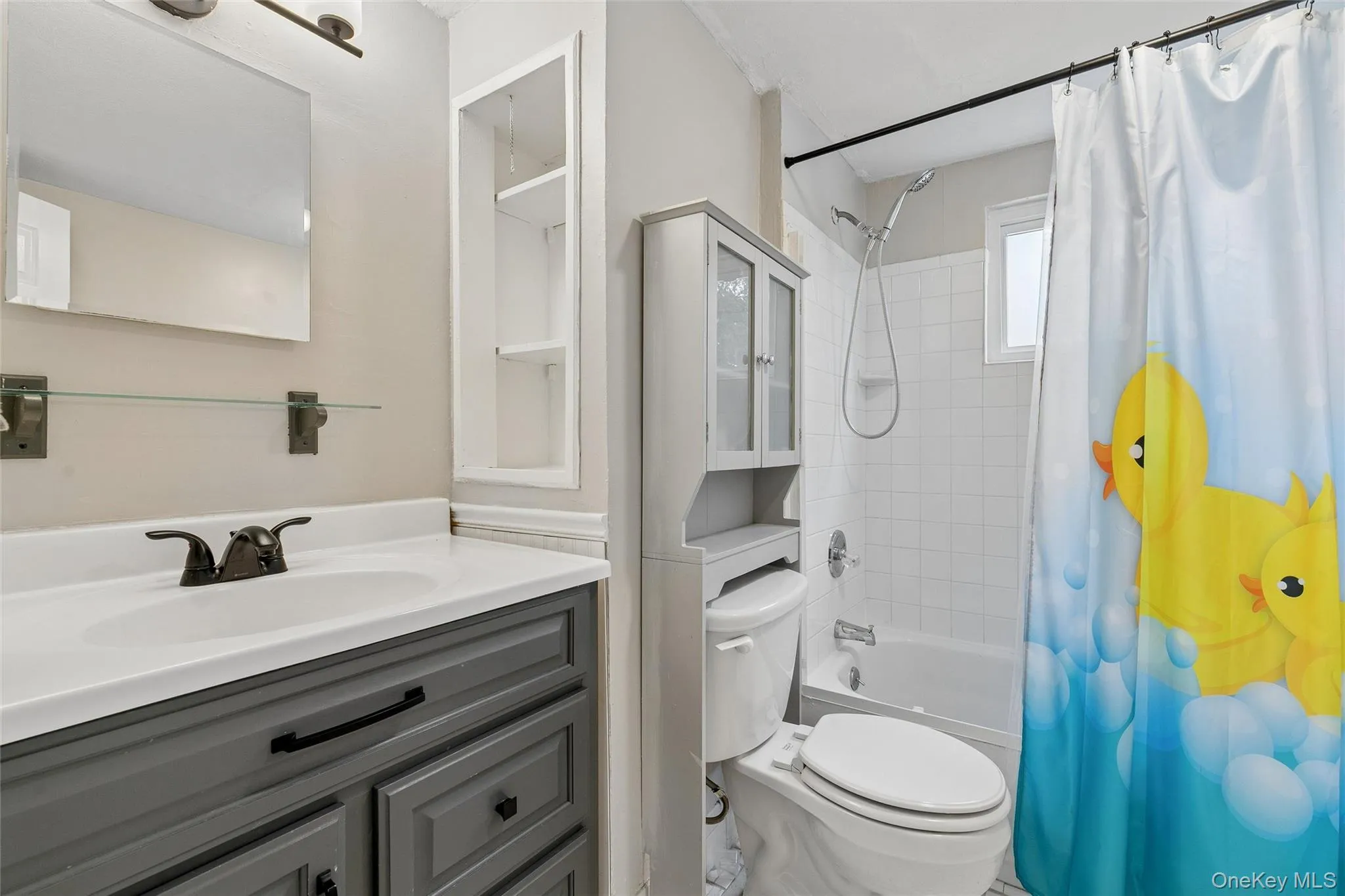 Bathroom featuring a vanity with dark gray cabinetry, white countertop, and dark-finish fixtures Bathroom featuring a vanity with dark gray cabinetry, white countertop, and dark-finish fixtures