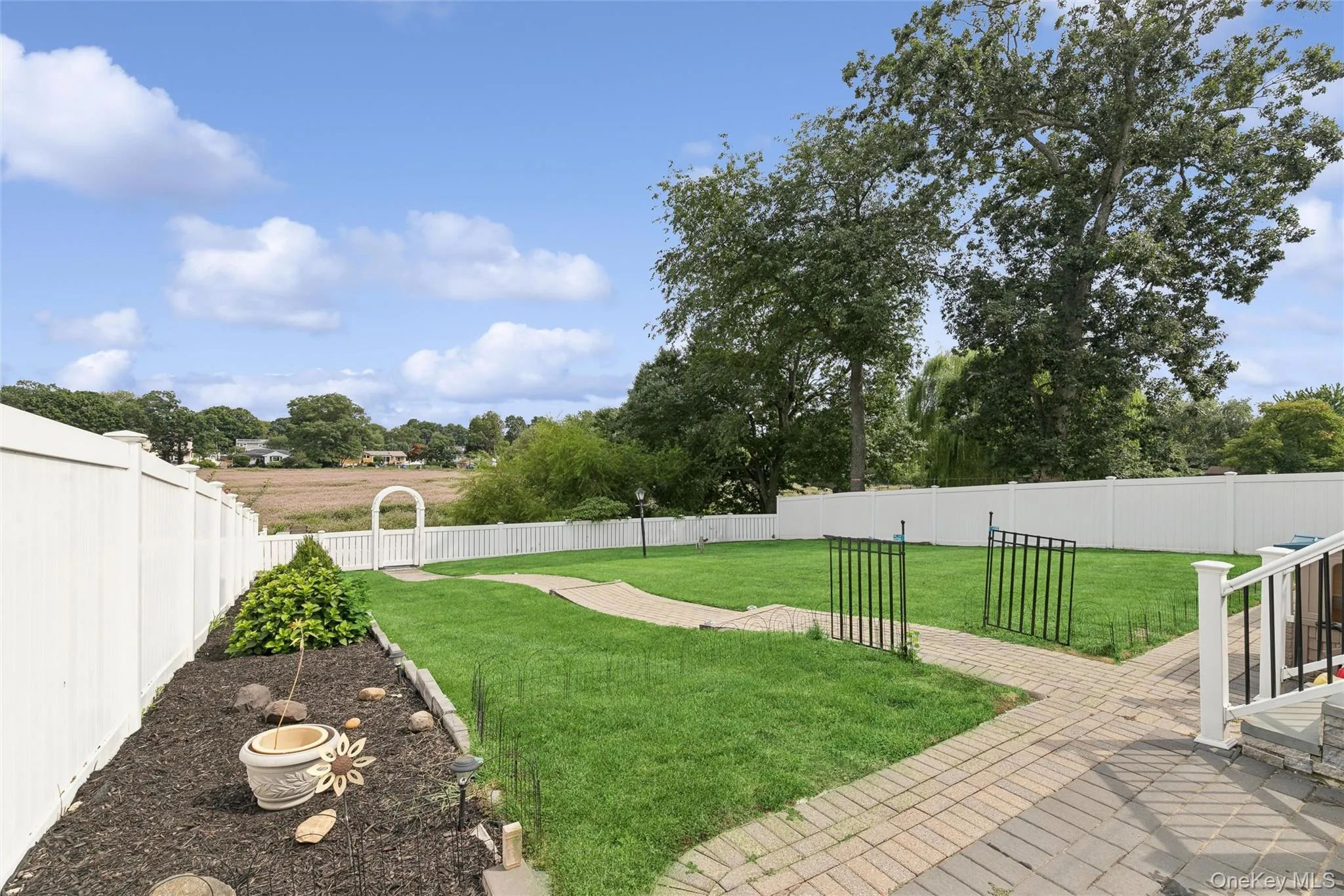 Expansive backyard featuring a white privacy fence, brick paver patio, and lawn space Expansive backyard featuring a white privacy fence, brick paver patio, and lawn space