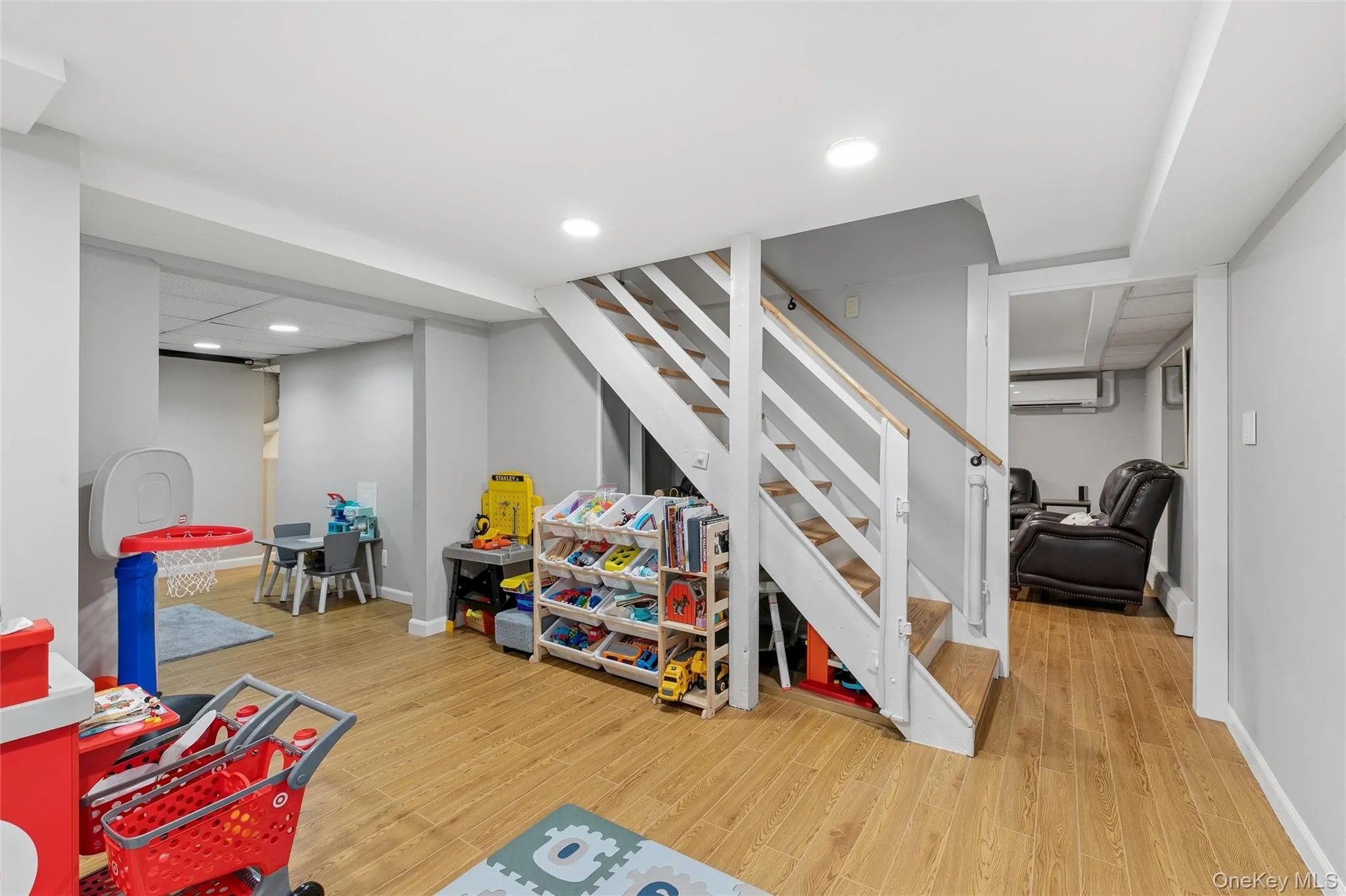 Wood-finish flooring throughout, recessed lighting, and a finished staircase with wood treads and white risers Wood-finish flooring throughout, recessed lighting, and a finished staircase with wood treads and white risers