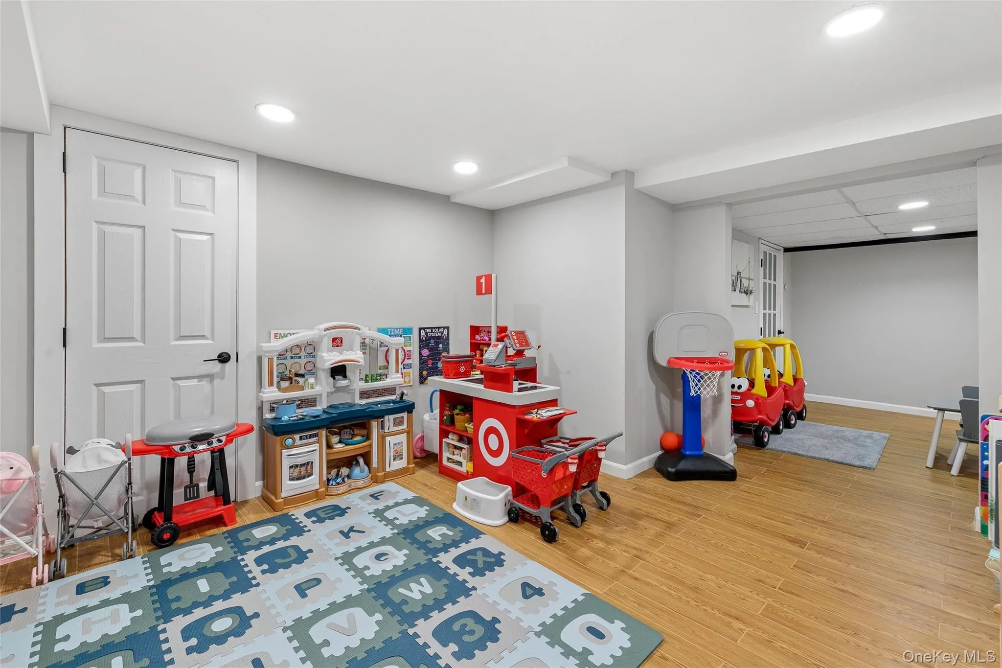 Spacious room featuring wood-finish flooring, recessed lighting, neutral wall tones, and white paneled doors Spacious room featuring wood-finish flooring, recessed lighting, neutral wall tones, and white paneled doors