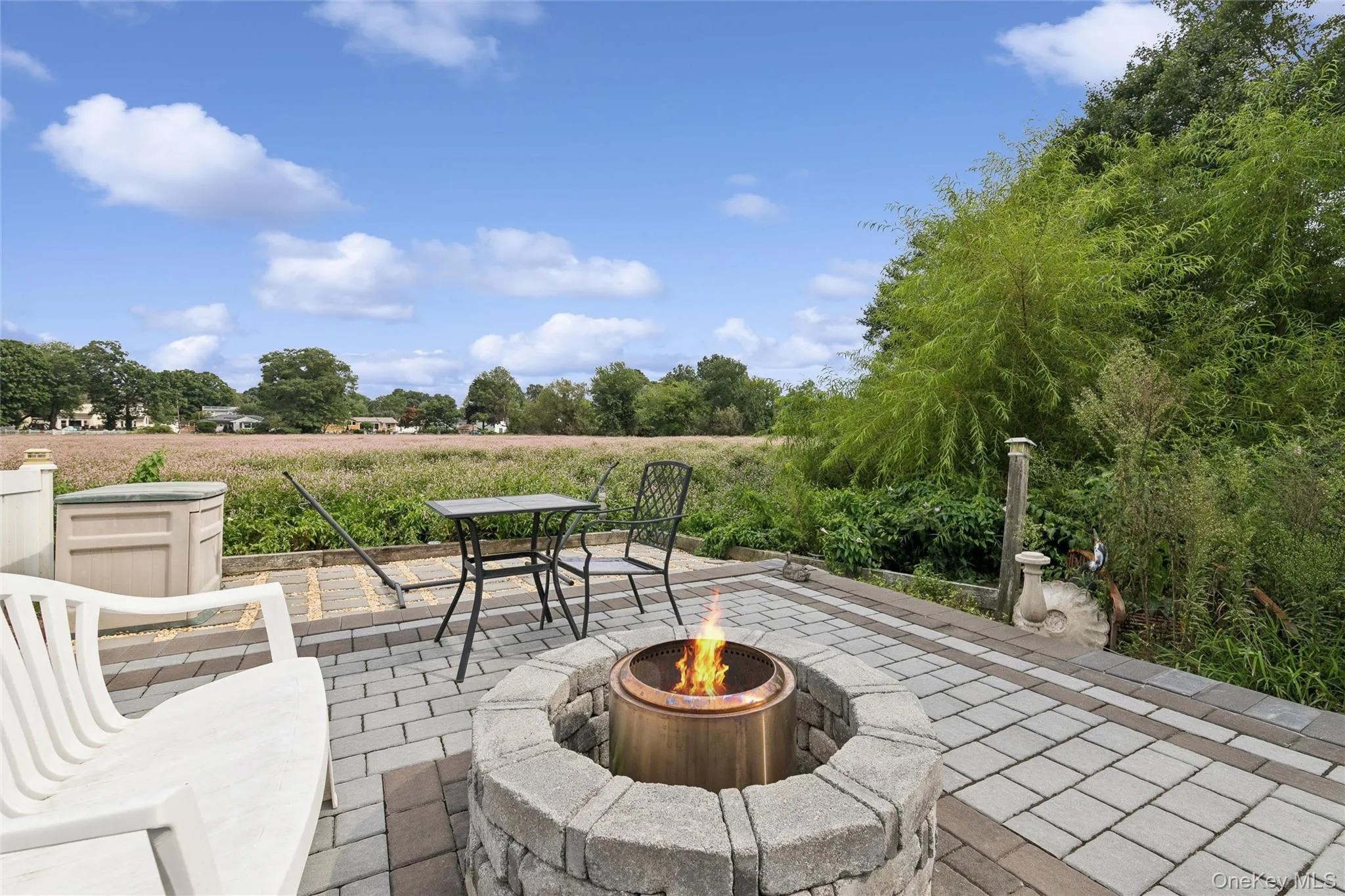 Paver patio with a stone fire pit and surrounding lush landscaping Paver patio with a stone fire pit and surrounding lush landscaping