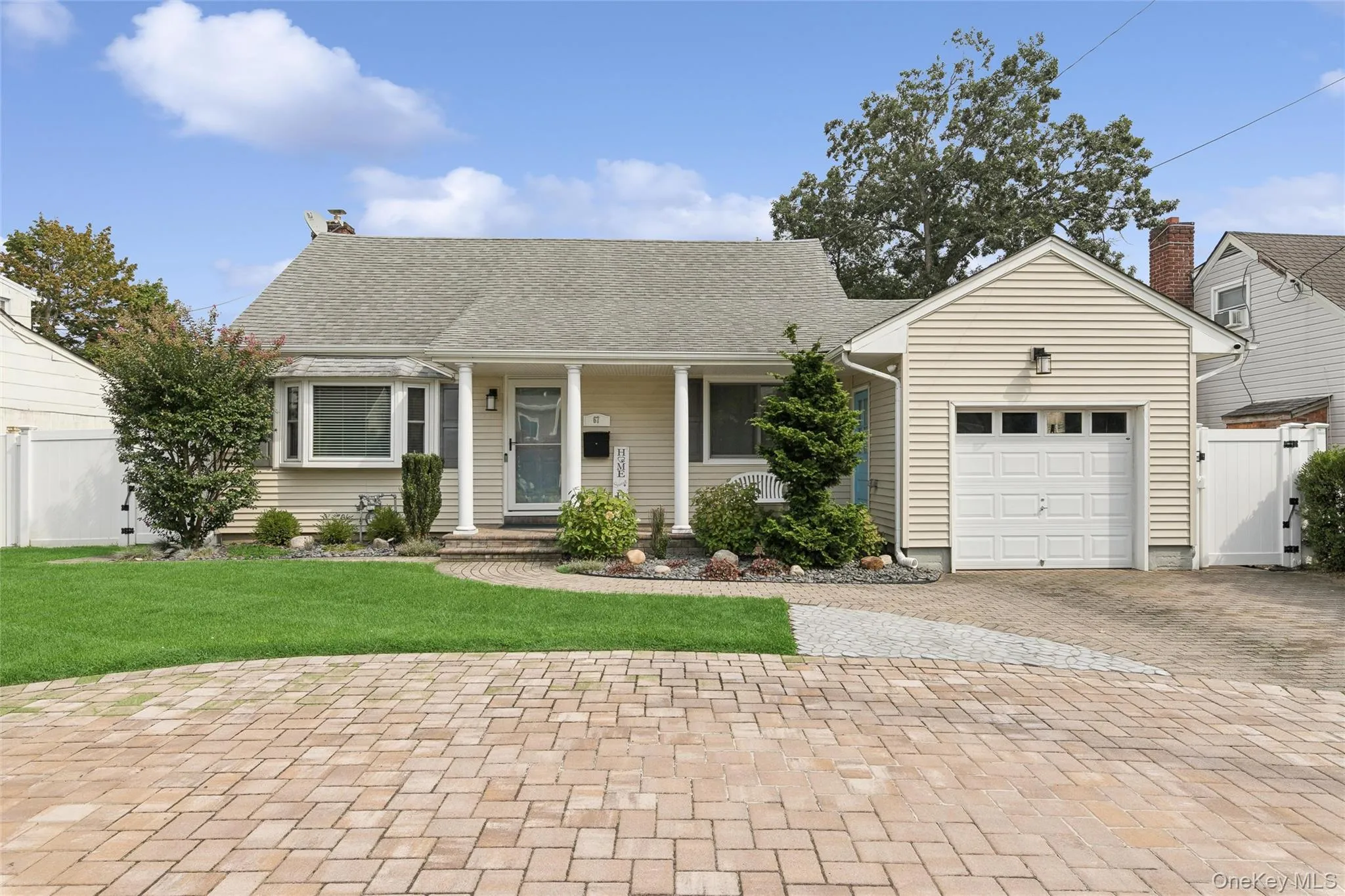 Siding exterior with a covered front entry, bay window, attached single-car garage, and a paver driveway Siding exterior with a covered front entry, bay window, attached single-car garage, and a paver driveway