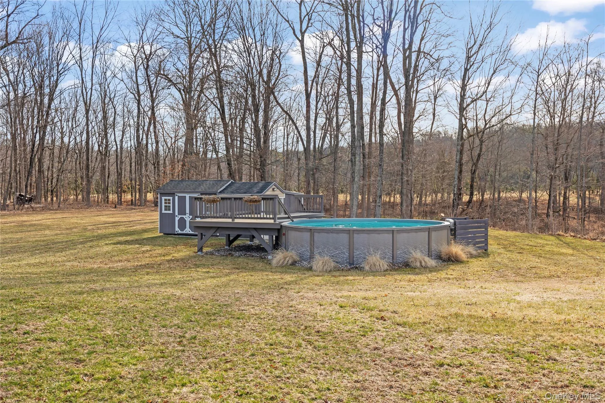 Outdoor pool with a yard, a wooded view, and a deck Outdoor pool with a yard, a wooded view, and a deck