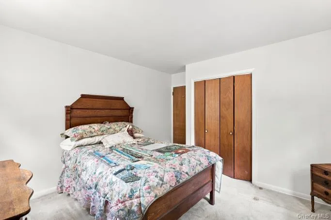 White walls, light-colored carpeting, and wood-finish bi-fold closet doors White walls, light-colored carpeting, and wood-finish bi-fold closet doors