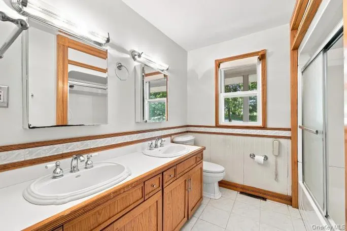 Double vanity with white oval sinks, white countertop, and wood-finish cabinetry Double vanity with white oval sinks, white countertop, and wood-finish cabinetry