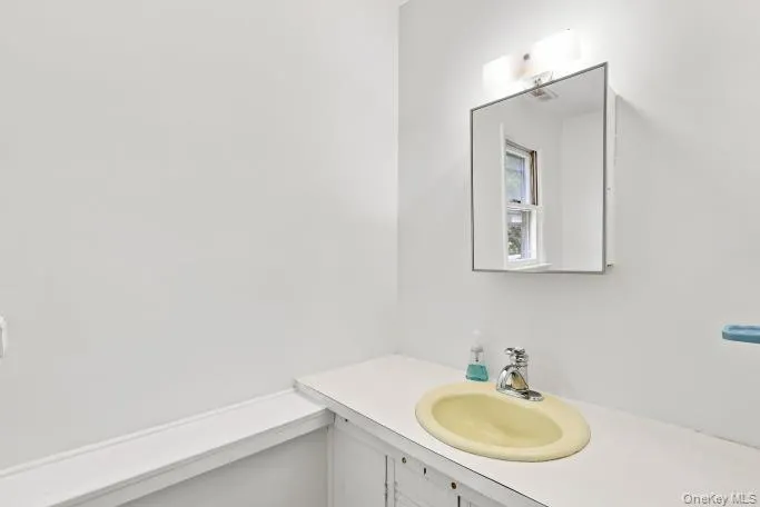 Built-in vanity with a drop-in sink, wall-mounted mirror, and overhead light fixture Built-in vanity with a drop-in sink, wall-mounted mirror, and overhead light fixture