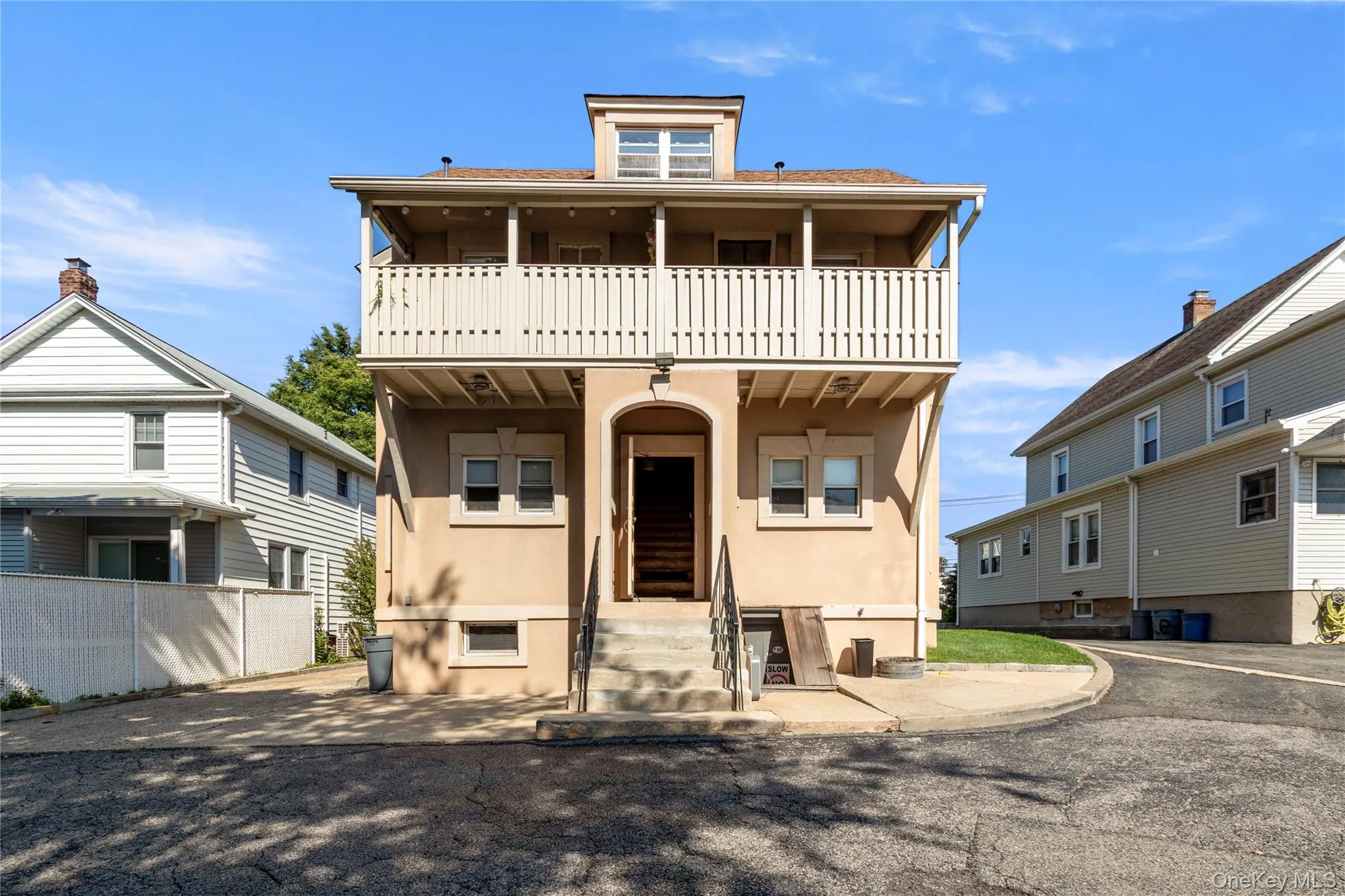 Stucco exterior featuring a prominent arched entry, upper-level balcony, and dormer window Stucco exterior featuring a prominent arched entry, upper-level balcony, and dormer window