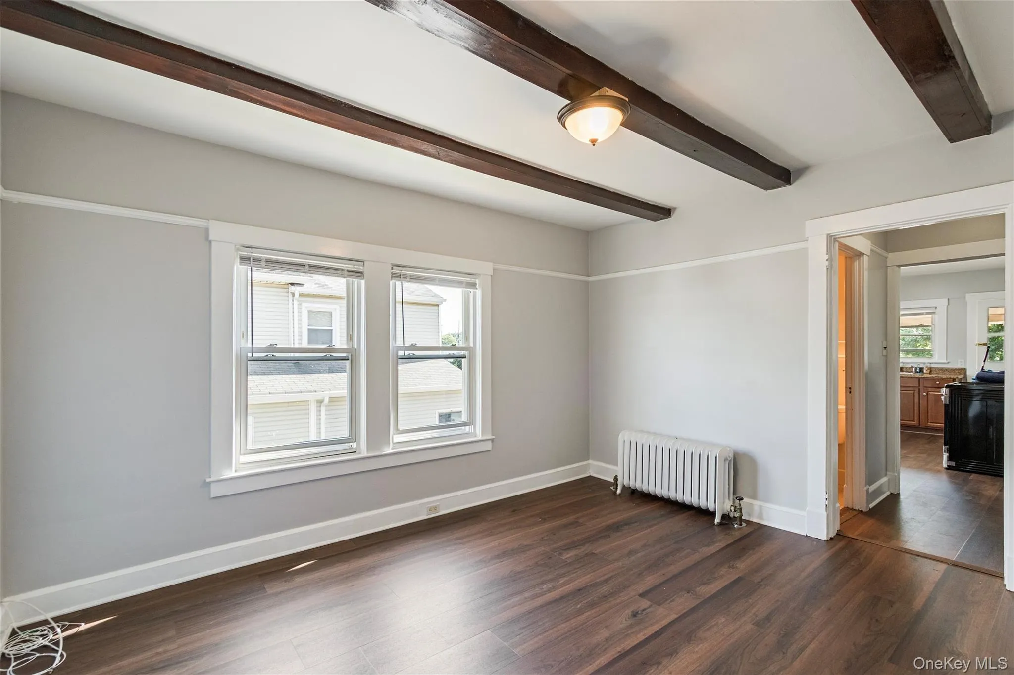 Wood-finish flooring with exposed ceiling beams and a semi-flush mount light fixture Wood-finish flooring with exposed ceiling beams and a semi-flush mount light fixture