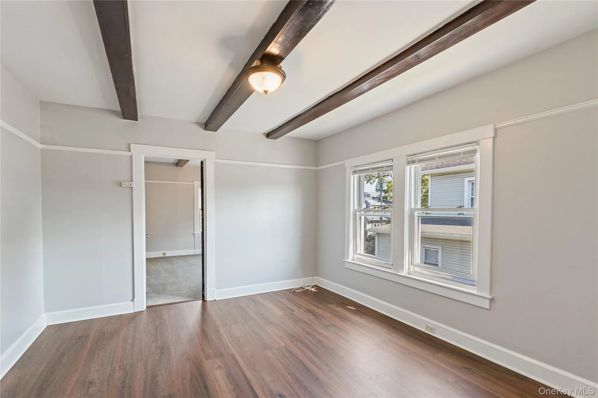 Exposed ceiling beams, wood-finish flooring, dual windows, ceiling light fixture, and white trim Exposed ceiling beams, wood-finish flooring, dual windows, ceiling light fixture, and white trim