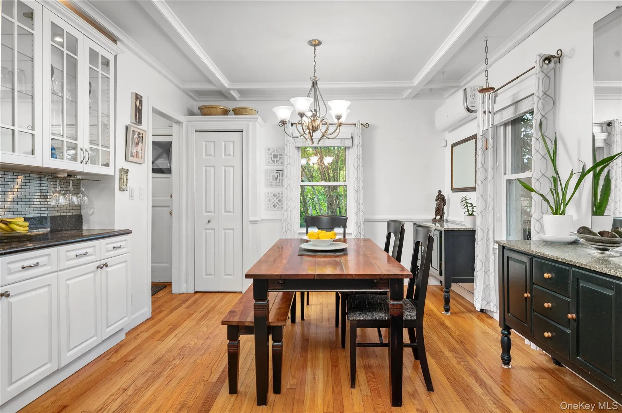 Hardwood flooring, white beamed ceiling, white cabinetry with bar set up and glass inserts Hardwood flooring, white beamed ceiling, white cabinetry with bar set up and glass inserts