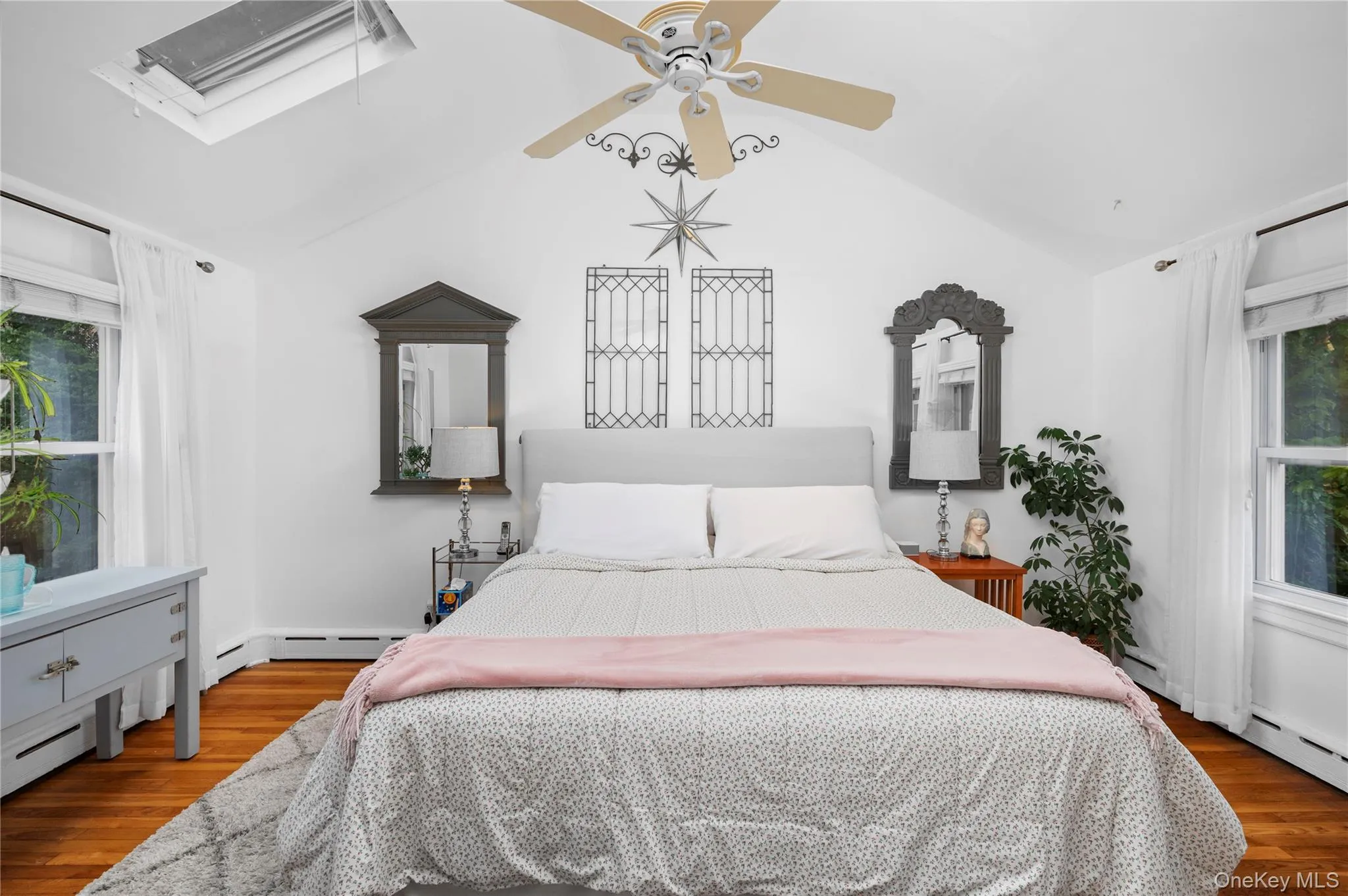 The primary bedroom offers cathedral ceiling with skylight and ceiling fan, hardwood flooring The primary bedroom offers cathedral ceiling with skylight and ceiling fan, hardwood flooring