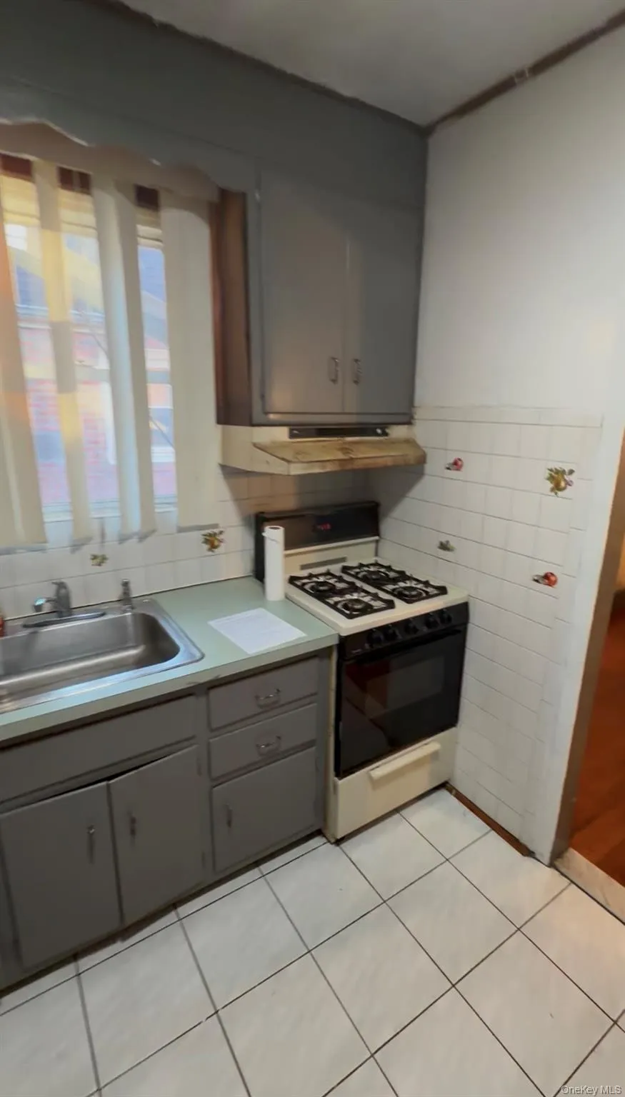 Kitchen featuring a gas range, stainless steel sink, tiled backsplash, and tiled flooring Kitchen featuring a gas range, stainless steel sink, tiled backsplash, and tiled flooring