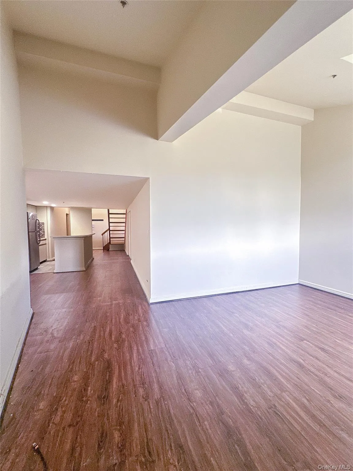 Bright and airy living room with impressive ceiling height, wood flooring, and an open-concept design. Bright and airy living room with impressive ceiling height, wood flooring, and an open-concept design.