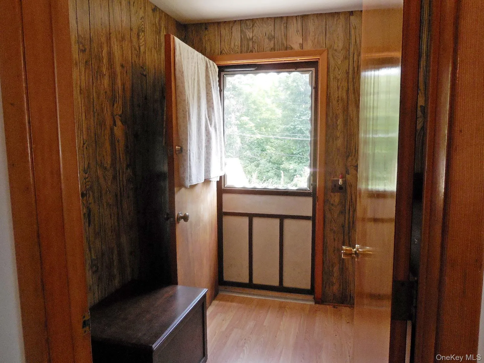 Wood-finish wall paneling, light wood-finish flooring, coat closet and storage shelves. Wood-finish wall paneling, light wood-finish flooring, coat closet and storage shelves.