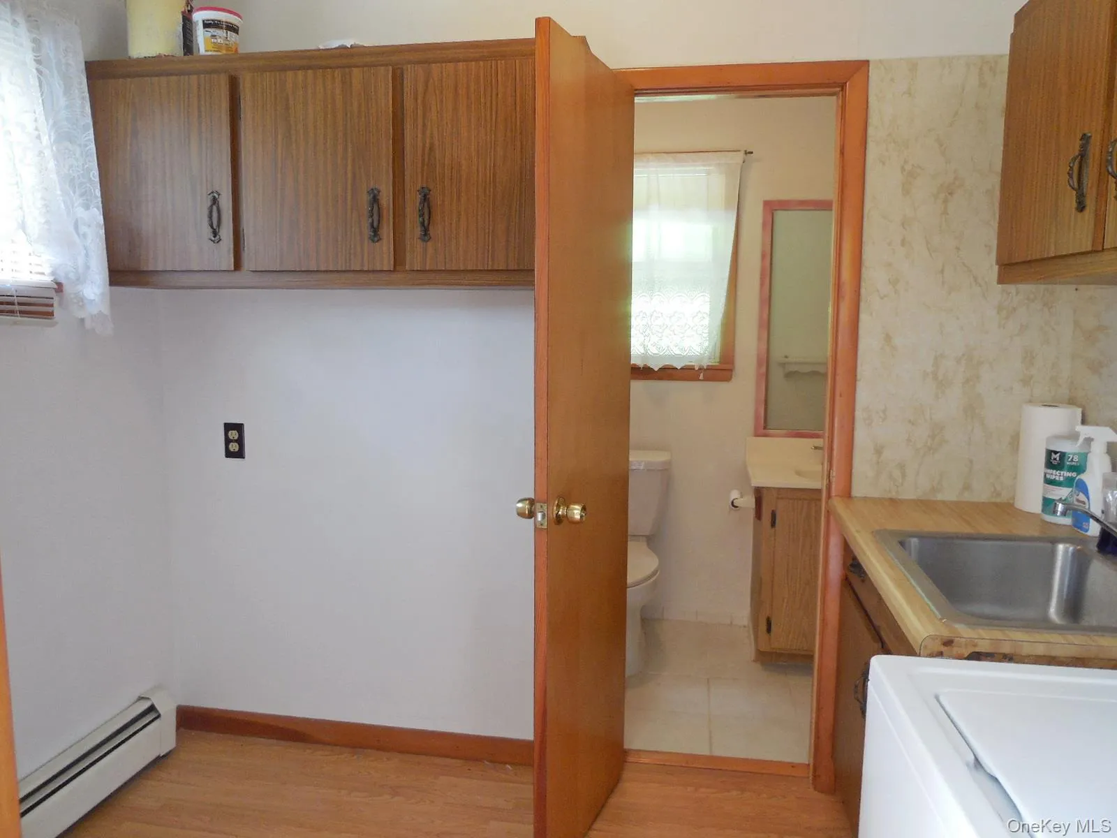 Wood-finish flooring, built-in upper cabinetry, and a utility sink with a stainless steel basin Wood-finish flooring, built-in upper cabinetry, and a utility sink with a stainless steel basin