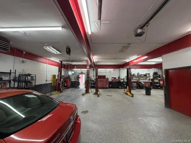 Large interior space with exposed support beams, fluorescent lighting, two vehicle lifts, and a durable concrete floor Large interior space with exposed support beams, fluorescent lighting, two vehicle lifts, and a durable concrete floor