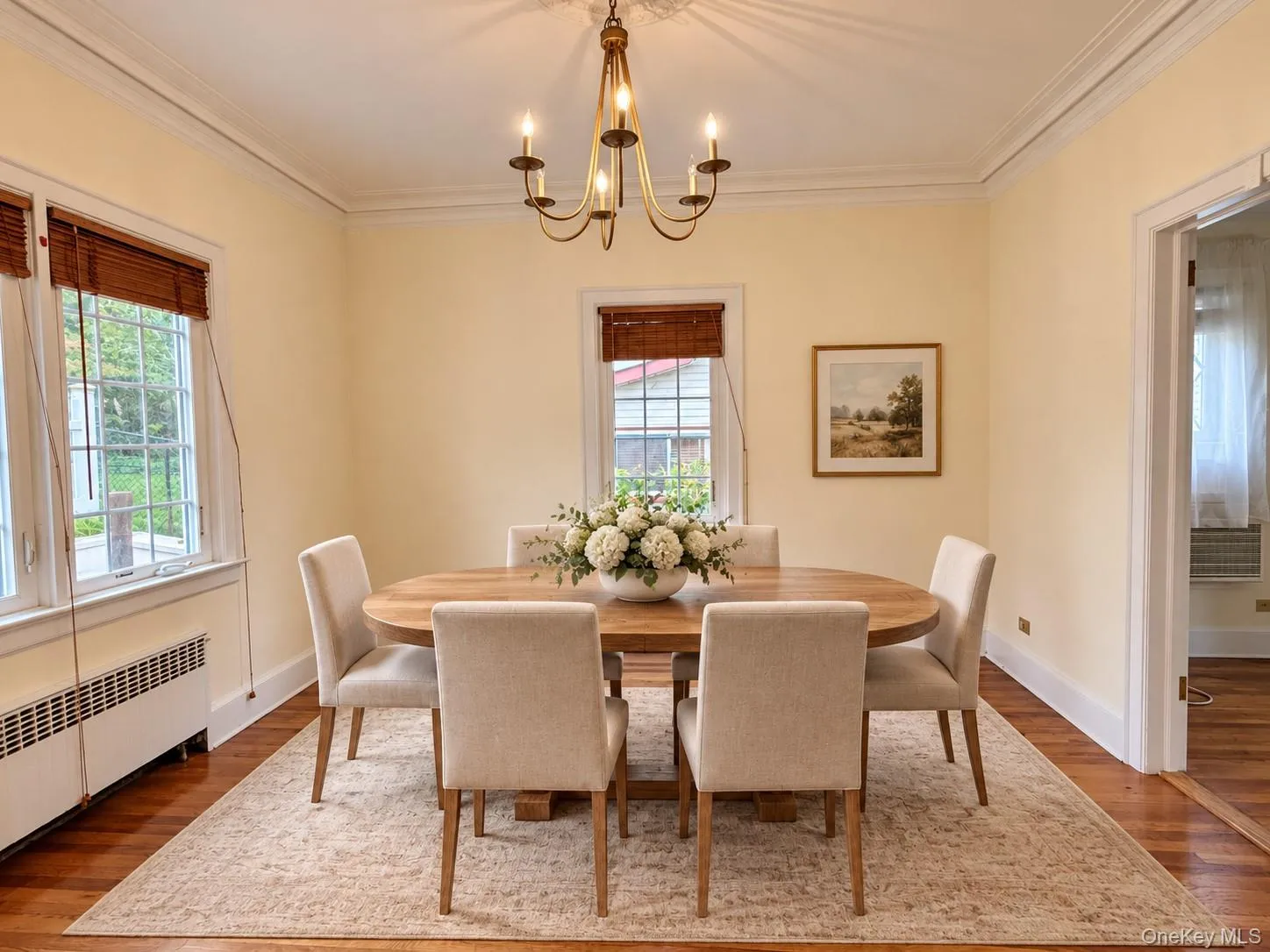 Dining area featuring wood-finish flooring, crown molding, and a multi-arm metal chandelier Dining area featuring wood-finish flooring, crown molding, and a multi-arm metal chandelier