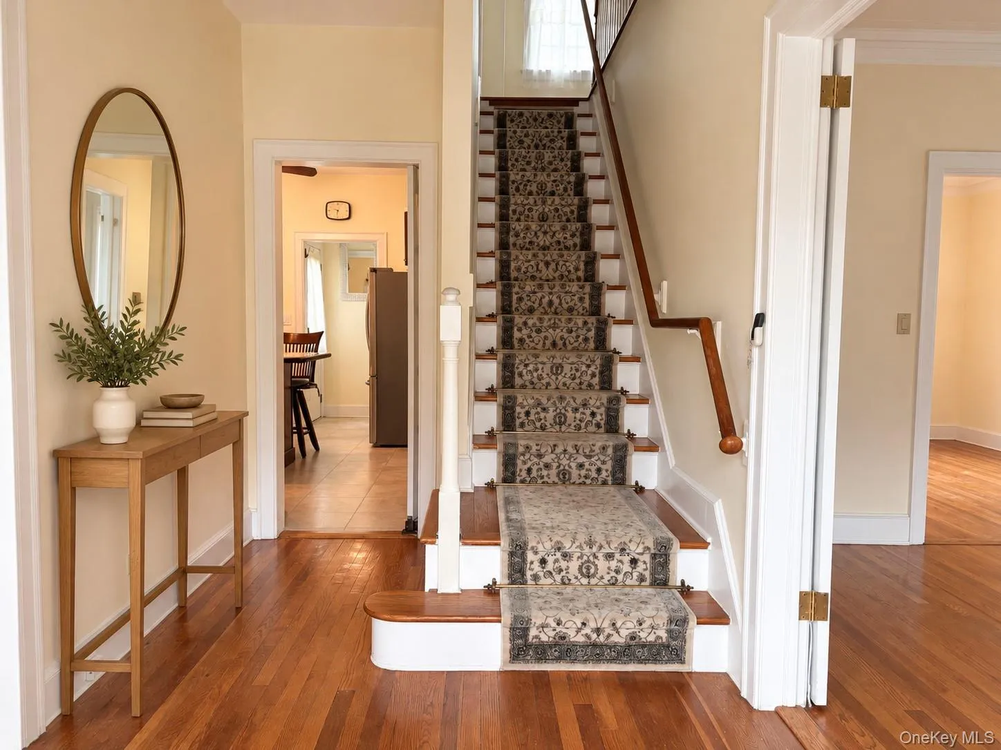 Foyer featuring hardwood flooring, a staircase with a wooden handrail, and patterned carpet runner Foyer featuring hardwood flooring, a staircase with a wooden handrail, and patterned carpet runner
