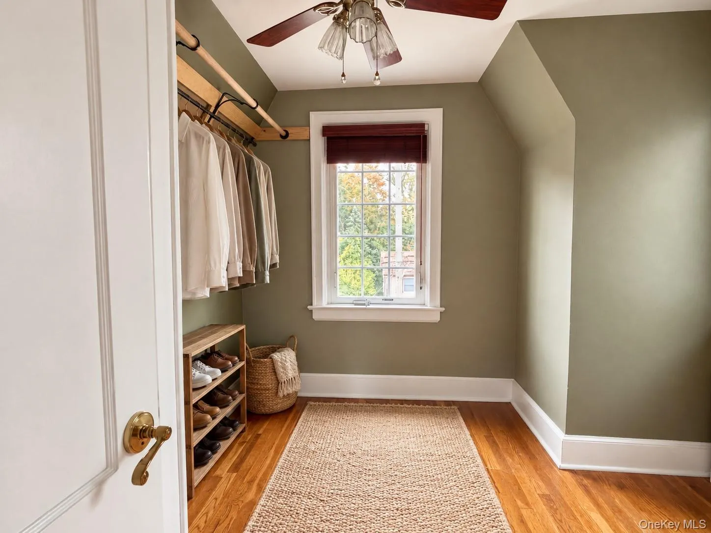Custom wooden closet rod, wood-finish flooring, multi-pane window with white casing, and ceiling-mounted light fixture Custom wooden closet rod, wood-finish flooring, multi-pane window with white casing, and ceiling-mounted light fixture