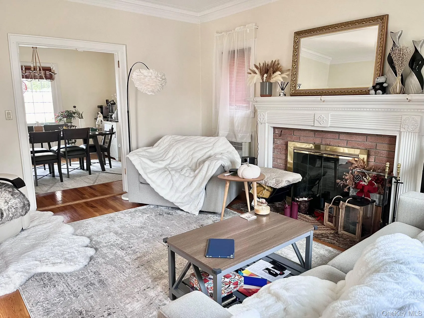 Built-in fireplace with brick surround and brass-toned firebox, detailed white mantelpiece, hardwood flooring, and crown molding Built-in fireplace with brick surround and brass-toned firebox, detailed white mantelpiece, hardwood flooring, and crown molding