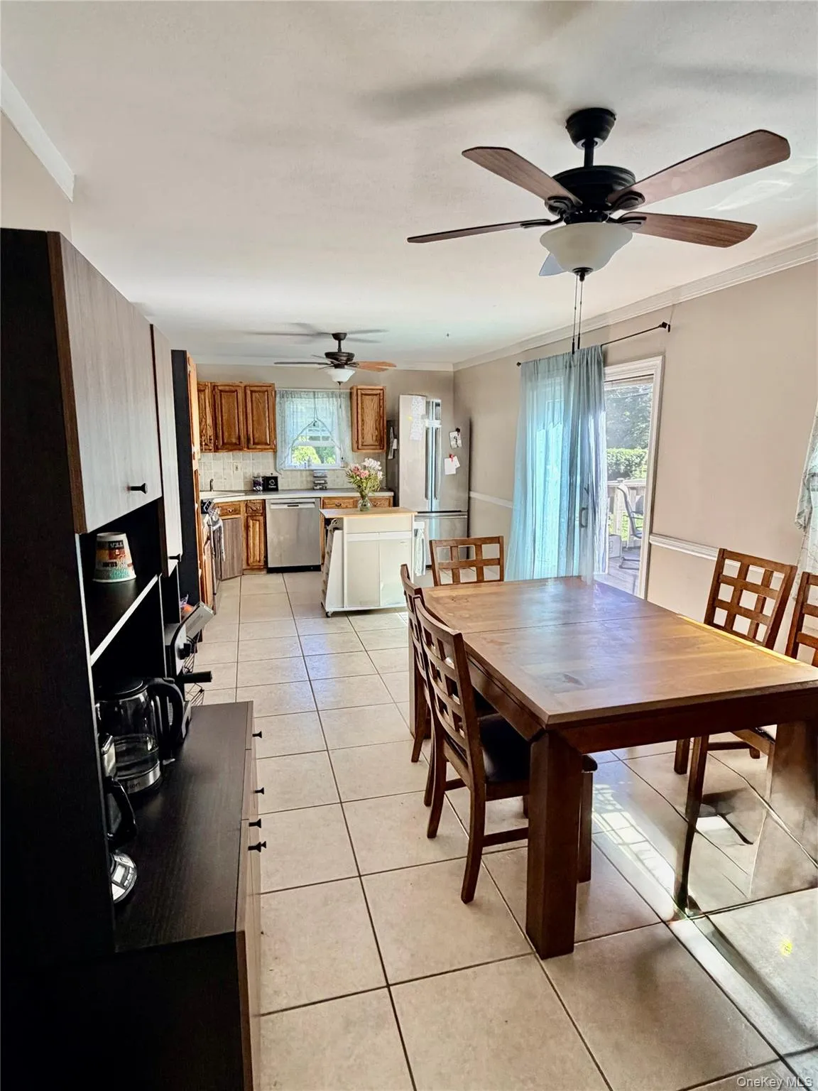Tile flooring throughout, two ceiling fans with integrated lighting, wood-finish cabinetry, stainless steel appliances, and a sliding glass door Tile flooring throughout, two ceiling fans with integrated lighting, wood-finish cabinetry, stainless steel appliances, and a sliding glass door