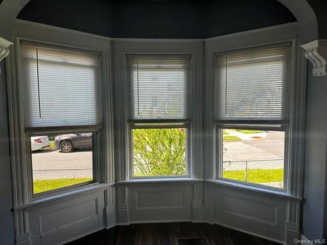 Bay window with three individual windows, detailed molding, and wood-finish flooring Bay window with three individual windows, detailed molding, and wood-finish flooring