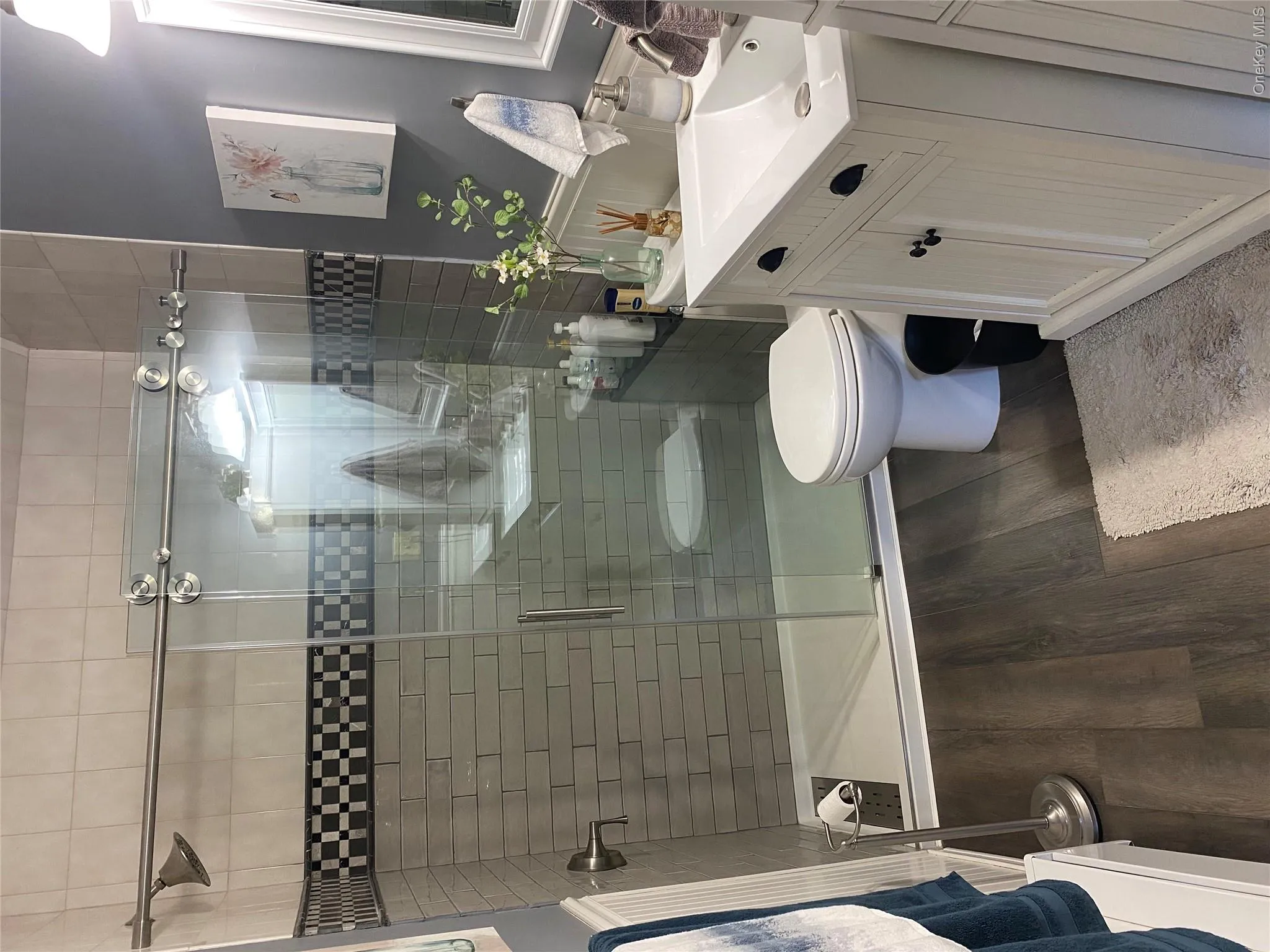 Glass-enclosed shower with subway tile surround, checkerboard accent tile, and a sliding door Glass-enclosed shower with subway tile surround, checkerboard accent tile, and a sliding door