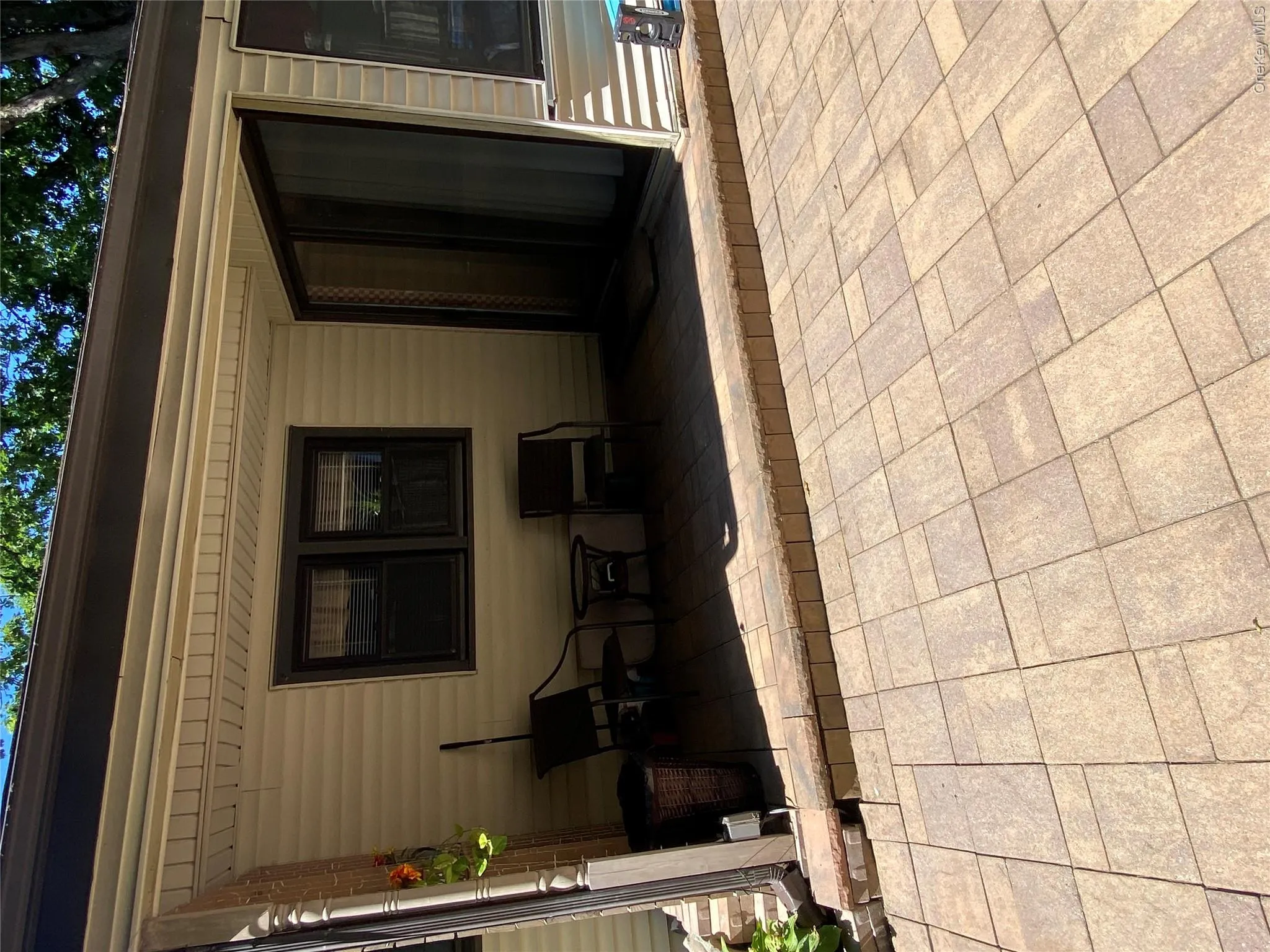 Paved patio area with a sliding glass door and two windows Paved patio area with a sliding glass door and two windows