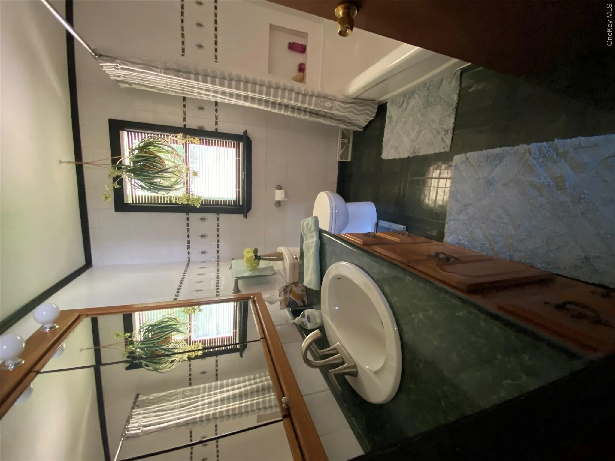 Bathroom featuring a wood vanity with an integrated sink, green countertop, and a built-in bathtub with shower Bathroom featuring a wood vanity with an integrated sink, green countertop, and a built-in bathtub with shower