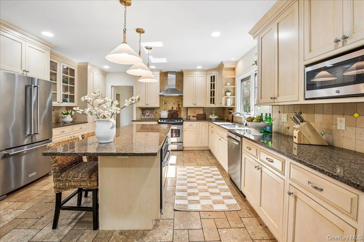 Spacious kitchen featuring an expansive center island with granite countertop, stainless steel appliances, recessed lighting, pendant lighting, and neutral tile flooring Spacious kitchen featuring an expansive center island with granite countertop, stainless steel appliances, recessed lighting, pendant lighting, and neutral tile flooring