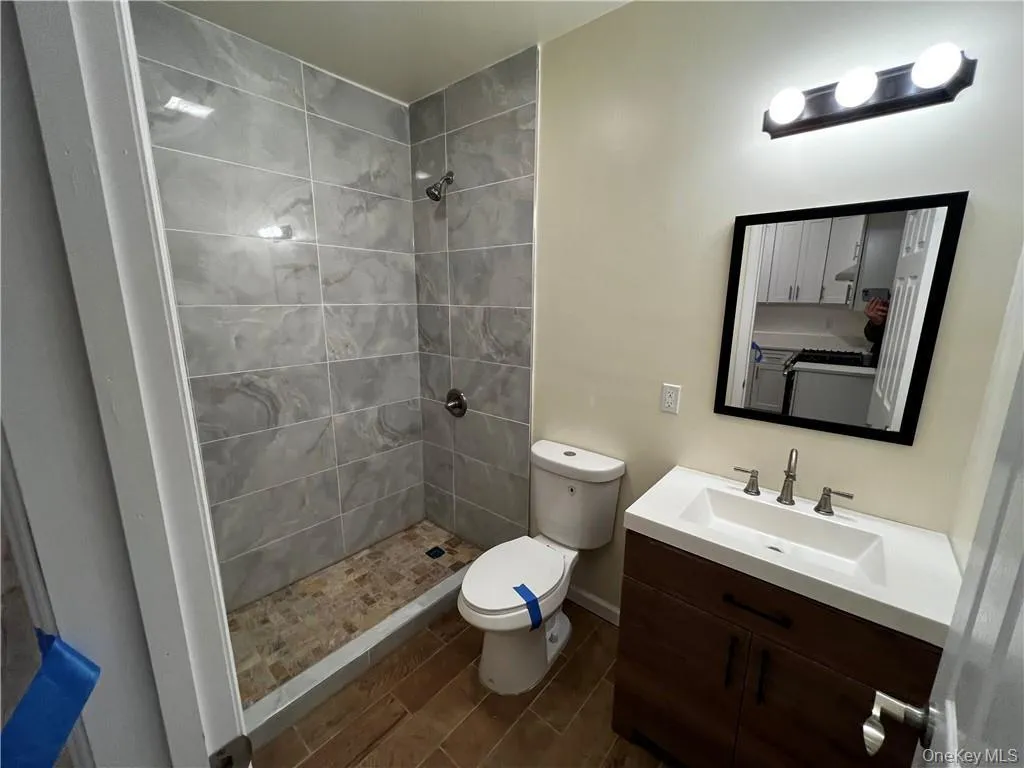 Bathroom with tiled shower, vanity, and toilet Bathroom with tiled shower, vanity, and toilet