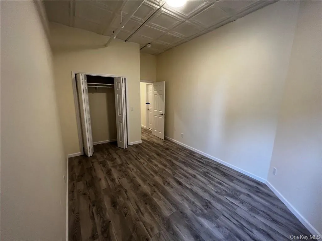 Unfurnished bedroom with dark hardwood / wood-style flooring and a closet Unfurnished bedroom with dark hardwood / wood-style flooring and a closet