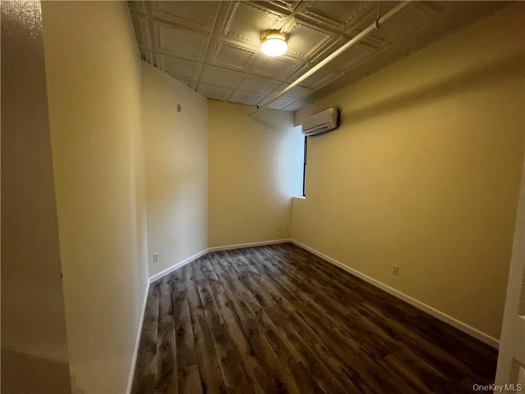 Unfurnished room with a wall mounted AC and dark hardwood / wood-style floors Unfurnished room with a wall mounted AC and dark hardwood / wood-style floors
