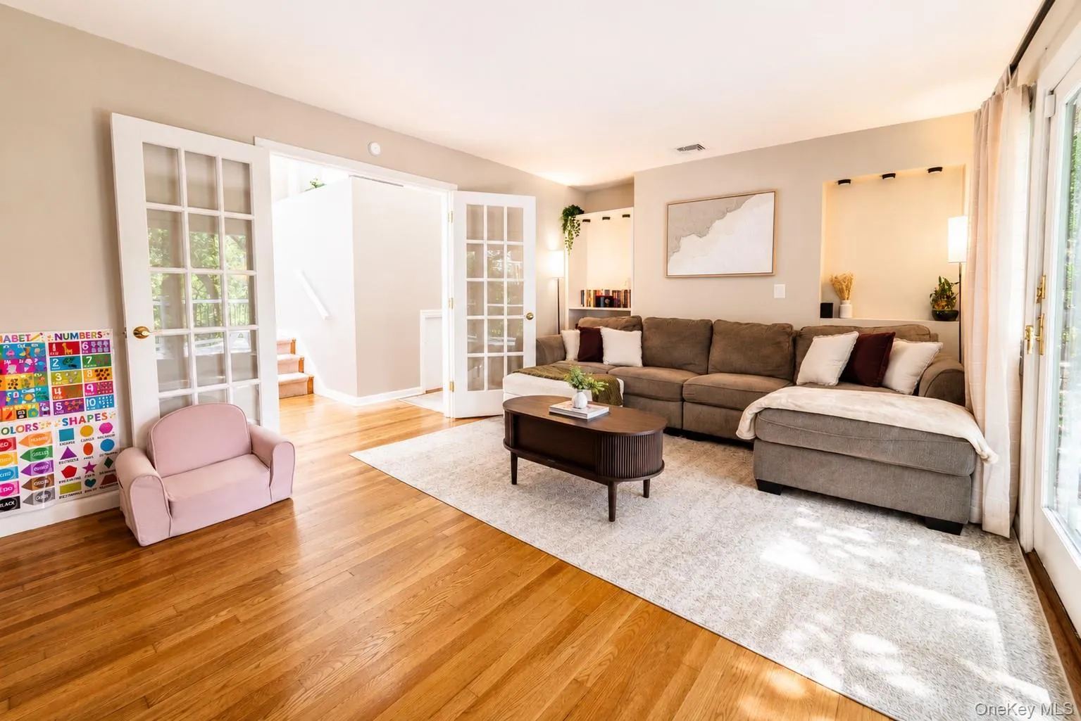 Another view of the spacious living room highlights the beautiful hardwood flooring and convenient access to the hallway bath, laundry room, and secondary bedroom, offering a comfortable and functional layout for everyday living. Another view of the spacious living room highlights the beautiful hardwood flooring and convenient access to the hallway bath, laundry room, and secondary bedroom, offering a comfortable and functional layout for everyday living.