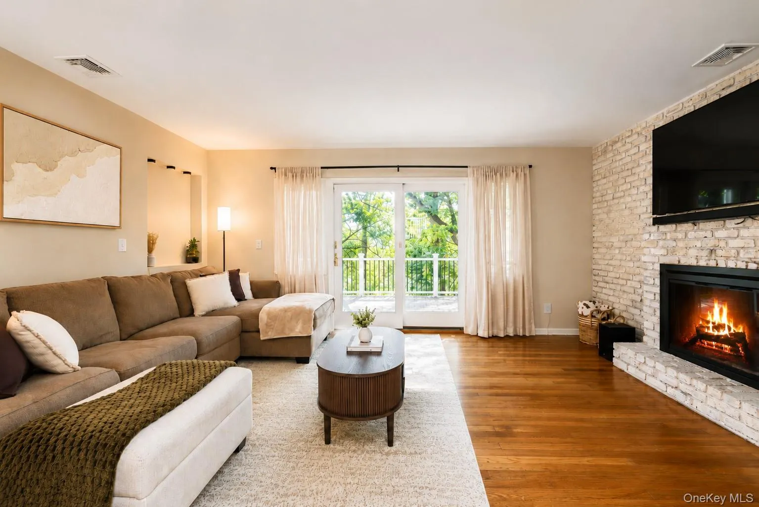The inviting main-level living room is anchored by a wood-burning fireplace and complemented by a charming brick accent wall, creating a warm and cozy atmosphere perfect for relaxing or entertaining. The inviting main-level living room is anchored by a wood-burning fireplace and complemented by a charming brick accent wall, creating a warm and cozy atmosphere perfect for relaxing or entertaining.
