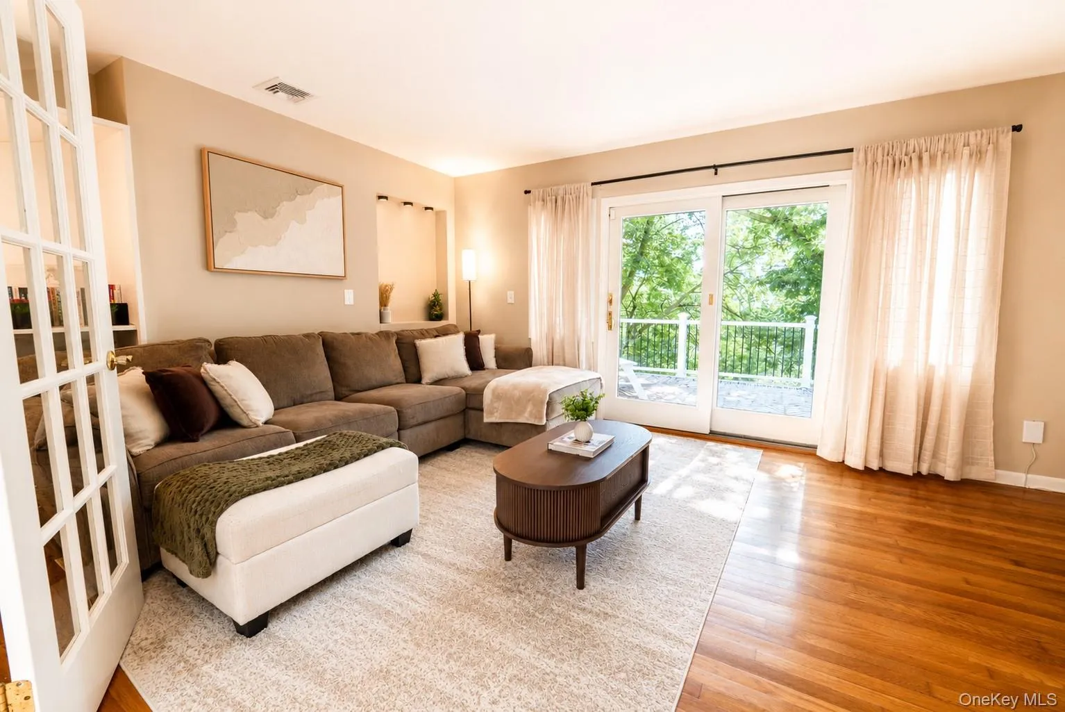 Another beautiful view of the living room showcases elegant French glass doors and sliding glass doors that provide seamless access to the deck, bringing in abundant natural light and creating an effortless connection to the outdoors. Another beautiful view of the living room showcases elegant French glass doors and sliding glass doors that provide seamless access to the deck, bringing in abundant natural light and creating an effortless connection to the outdoors.