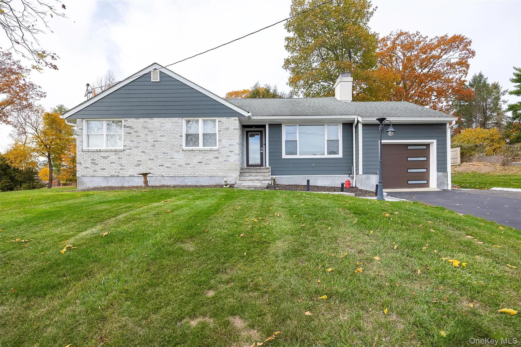 Ranch-style house featuring an attached garage, a front lawn, driveway, and a chimney Ranch-style house featuring an attached garage, a front lawn, driveway, and a chimney