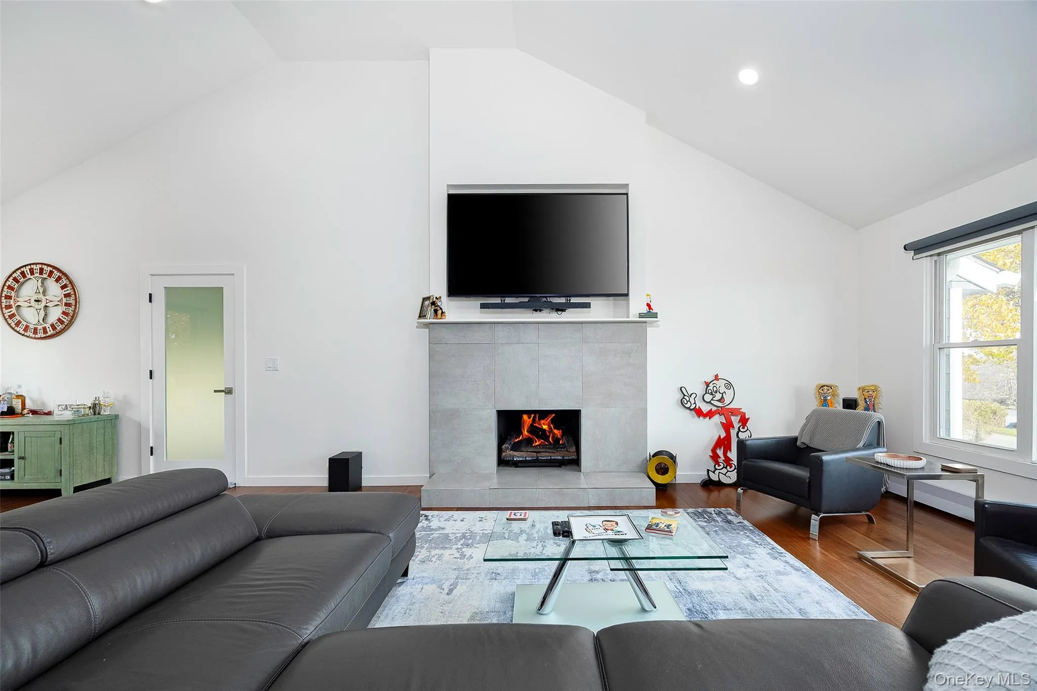 Living area with a tile fireplace, wood finished floors, high vaulted ceiling, and recessed lighting Living area with a tile fireplace, wood finished floors, high vaulted ceiling, and recessed lighting
