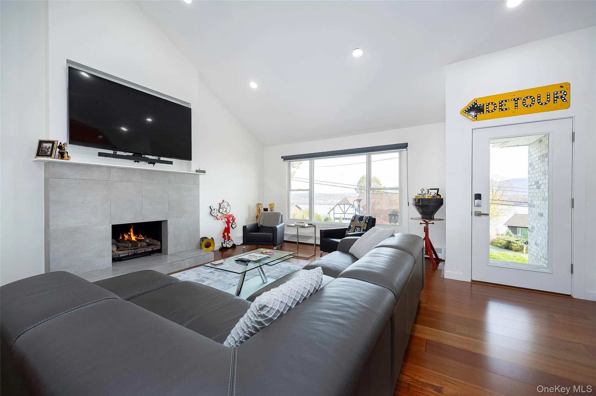 Living room featuring high vaulted ceiling, dark wood-style flooring, recessed lighting, and a fireplace Living room featuring high vaulted ceiling, dark wood-style flooring, recessed lighting, and a fireplace
