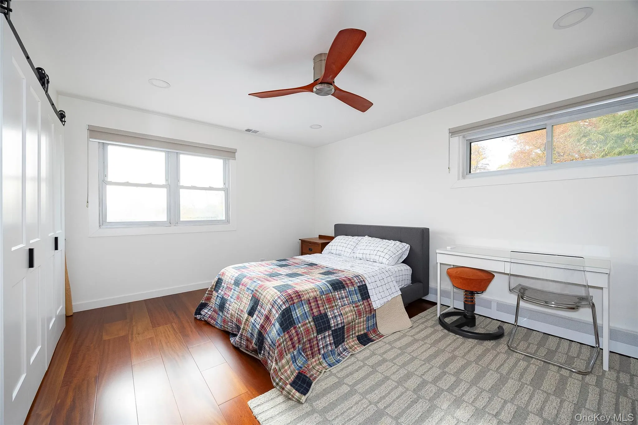 Bedroom with a closet, a barn door, a ceiling fan, wood finished floors, and recessed lighting Bedroom with a closet, a barn door, a ceiling fan, wood finished floors, and recessed lighting