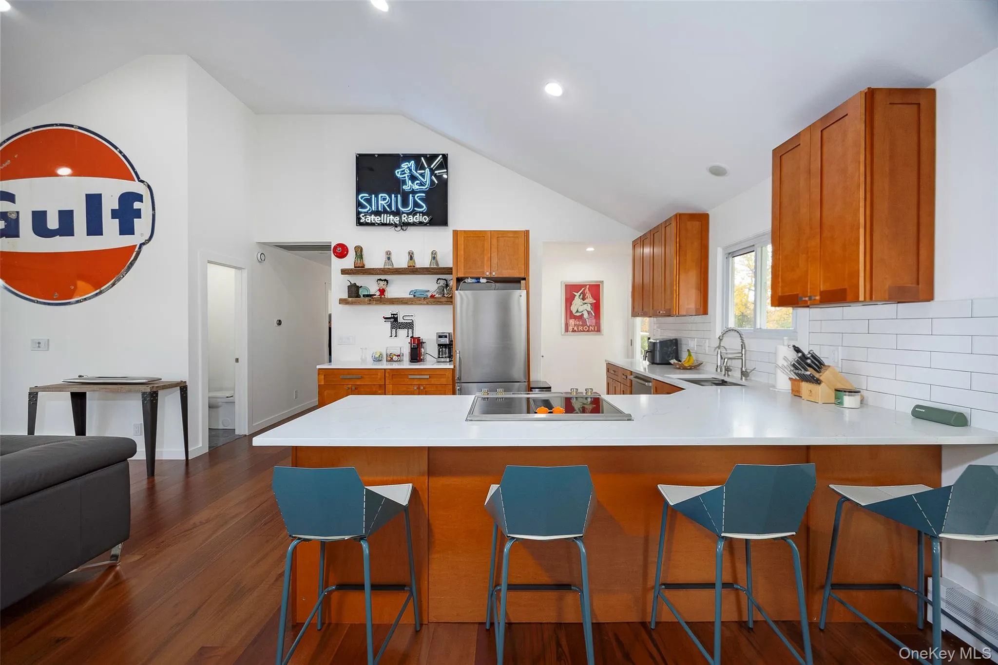 Kitchen with brown cabinets, dark wood-style flooring, a kitchen bar, freestanding refrigerator, and a peninsula Kitchen with brown cabinets, dark wood-style flooring, a kitchen bar, freestanding refrigerator, and a peninsula