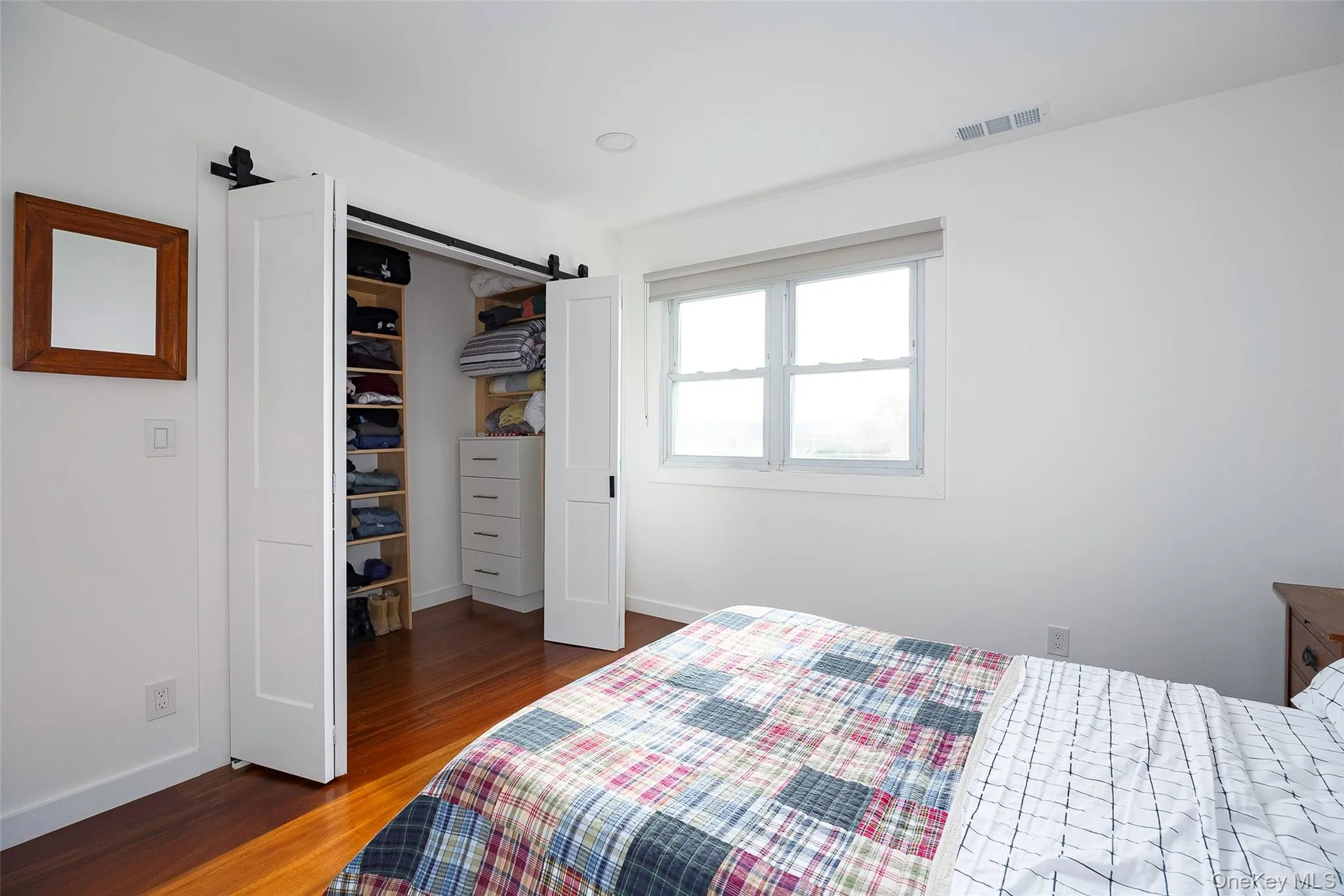 Bedroom with a barn door, dark wood-type flooring, and a closet Bedroom with a barn door, dark wood-type flooring, and a closet