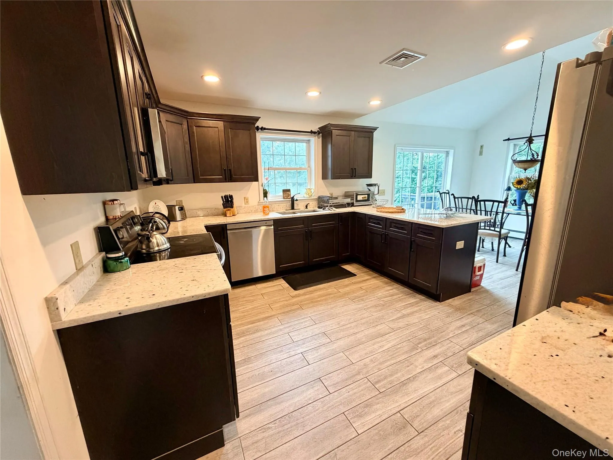 Kitchen featuring dark wood cabinetry, light speckled granite countertops, stainless steel appliances, granite tile flooring, and recessed lighting Kitchen featuring dark wood cabinetry, light speckled granite countertops, stainless steel appliances, granite tile flooring, and recessed lighting